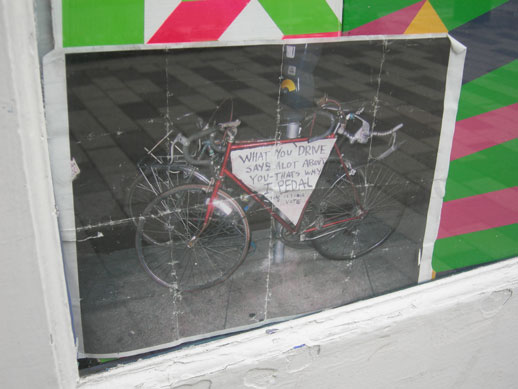 Sign reads: 'What you drive says a lot about you - That's why I pedal. Your $ is your vote'