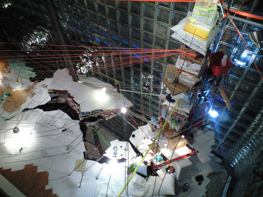 An 8m-high pile of various objects anchored to different beams and points in the space.