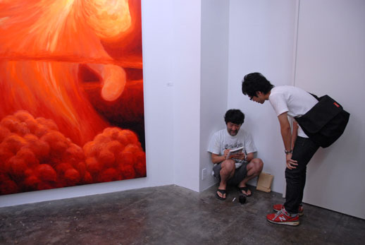 Makoto Aida, sitting next to his large-scale ''Moco Moco'' painting at the opening of his solo show at Mizuma Art Gallery in August.