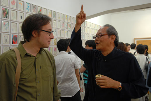 Gallery owner Sueo Mitsuma (right) tells Roger McDonald from Arts Initiative Tokyo (left) about the exhibition in their 5th floor space.