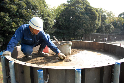 A construction worker adds the final touches to the top of the cylinder.