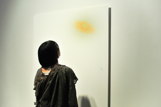 A visitor staring at one of the paintings exhibited in the first room of the gallery.