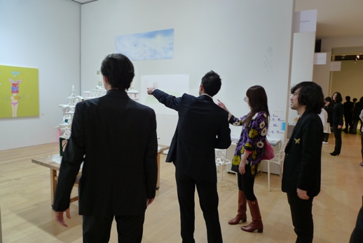 Artist Teppei Kaneuji (right) looks on as visitors discuss his work and others' at the Shugoarts booth.