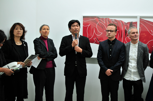Yusaku Imamura, director of Tokyo Wonder Site, speaking. Behind the group is 'Untitled', by Maria Hahnnenkamp, from the series 'Dress'.