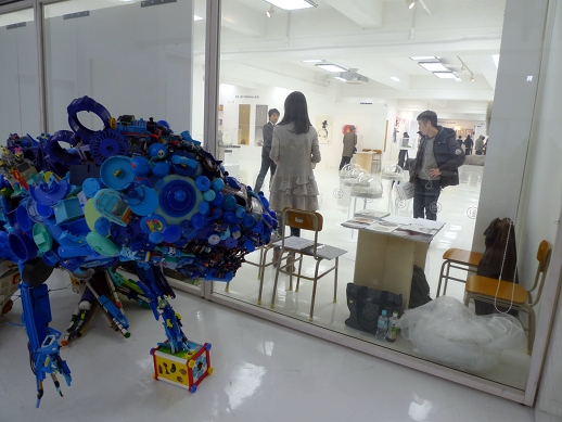 The 'Exchange' space seen from behind the window at the Insideout/Tokyo Project room, with 'Toysaurus' by Hiroshi Fuji.