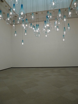 Tobias Rehberger's 'Anderer' (2002):
59 light bulbs hang from the ceiling, connected to a remote child's room by the internet.
When the light in the child's room switches off, they turn on in the Museum. Switched back on over there, they will turn off here.