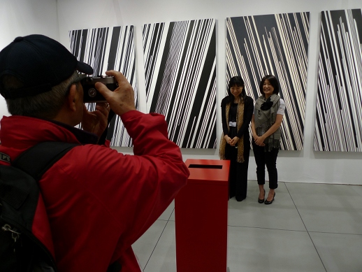 Staff at SCAI The Bathhouse's booth get their photo taken. Behind them are works from Kohei Nawa's 'Direction' series.