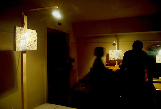 千葉正也の作品。薄暗い空間でのインスタレーション。絵画をかけている木材や照明もセットで一つの作品だそう。